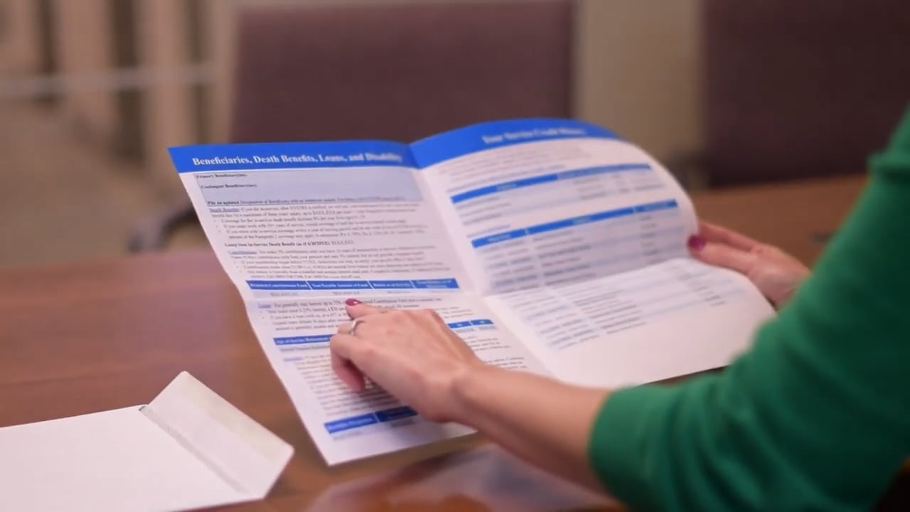 A woman's hands are seen holding and pointing at a printed Benefit Profile.