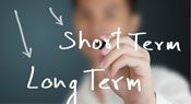 A man writing on glass with a marker with arrows pointing to short term and long term.