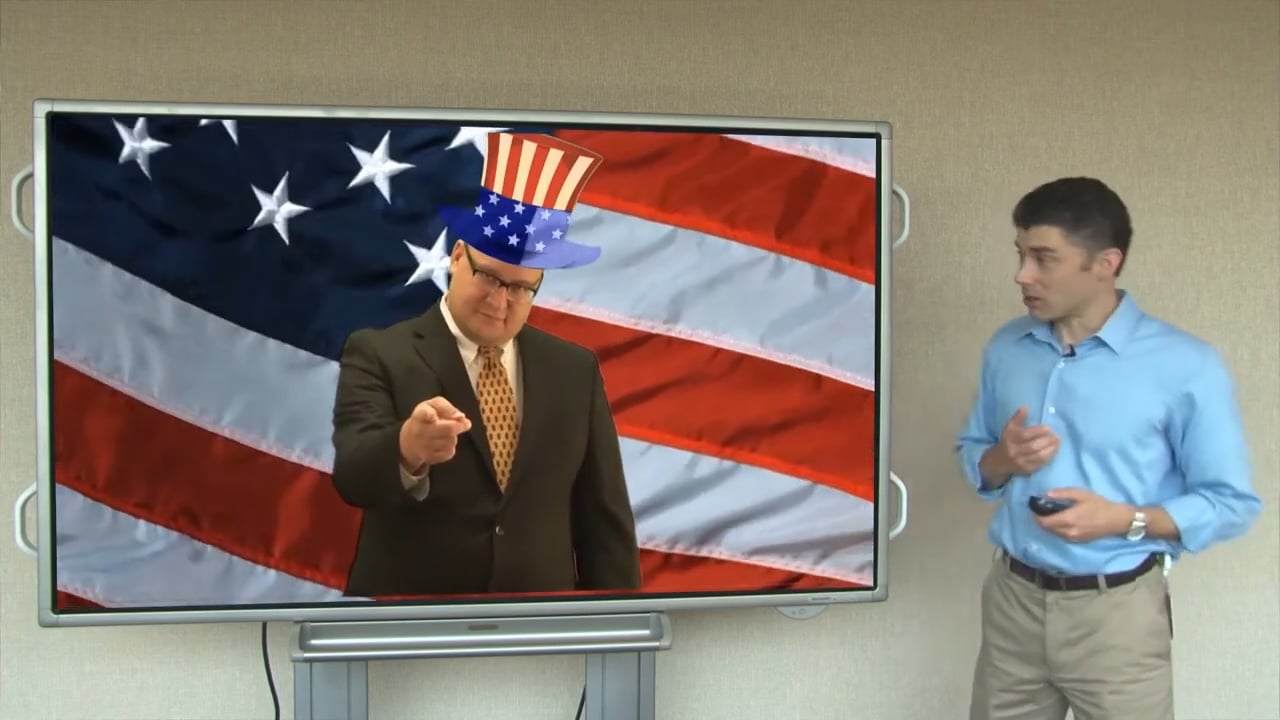 A man is holding a remote looking at a TV showing a man in a suit with an Uncle Sam hat pointing.